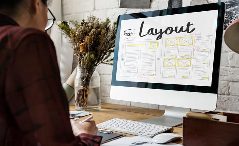 Webdesigner nutzt Webdesign Tools und sitzt vor ihrem Monitor mit einer Layout-Seite offen